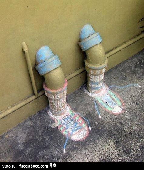 Tubi che escono dal muro come due gambe con scarpe, calzini e pantaloncini corti