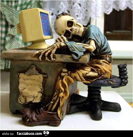 Statuetta di scheletro seduto davanti al computer