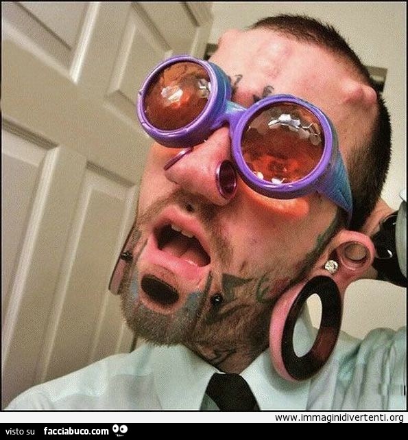 Ragazzo con occhiali viola tatuato con i piercing